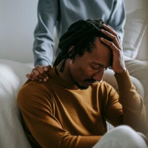 man with head in hand with partner touching shoulders